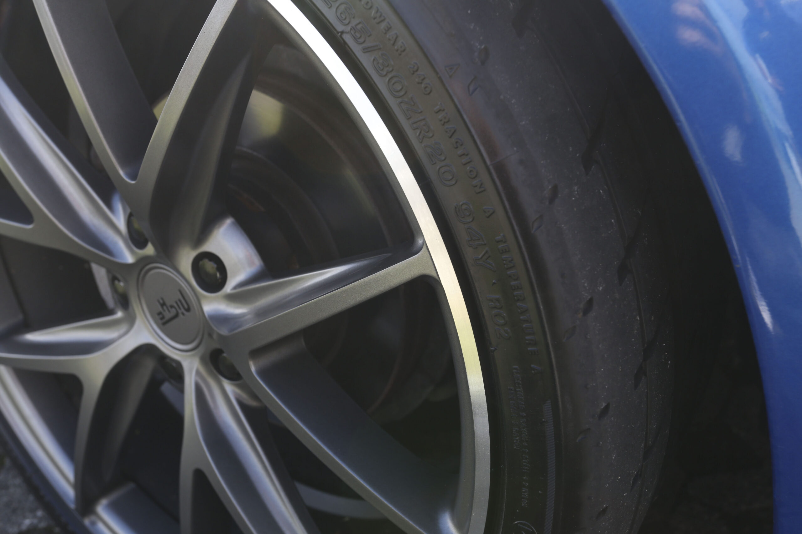 A finished machined-face gunmetal alloy wheel fitted to a blue car